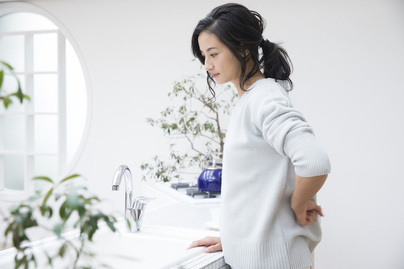 腰を抑えている女性